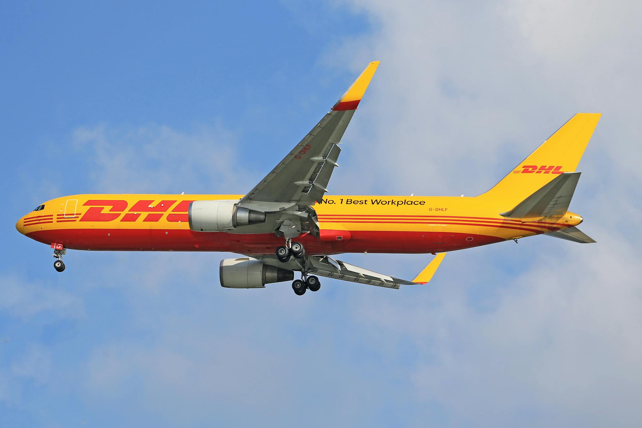 A DHL cargo airplane flying high in the clear blue sky, showcasing transportation efficiency.