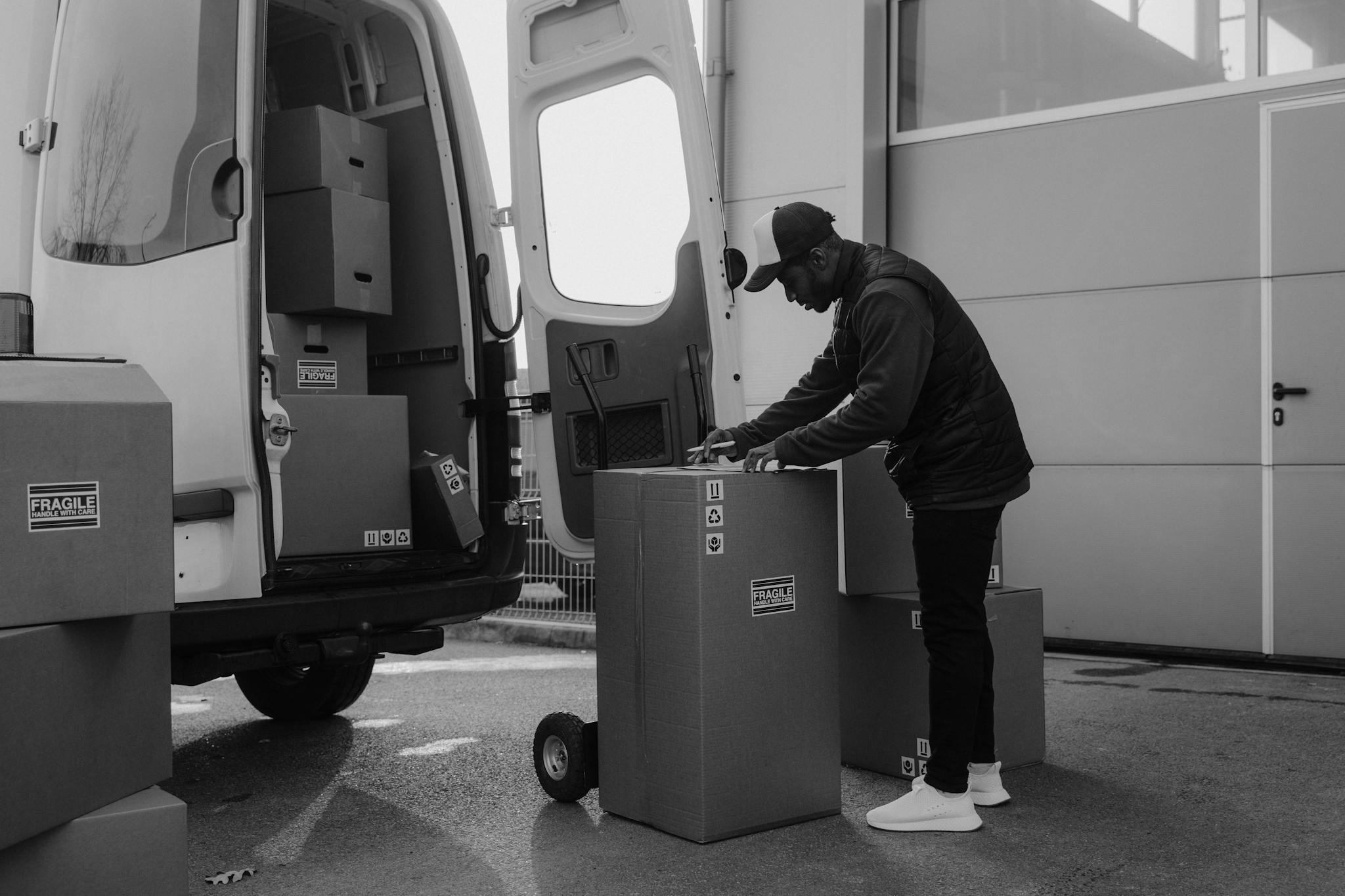 Delivery driver organizing packages near a van in an urban setting, ready for shipping.